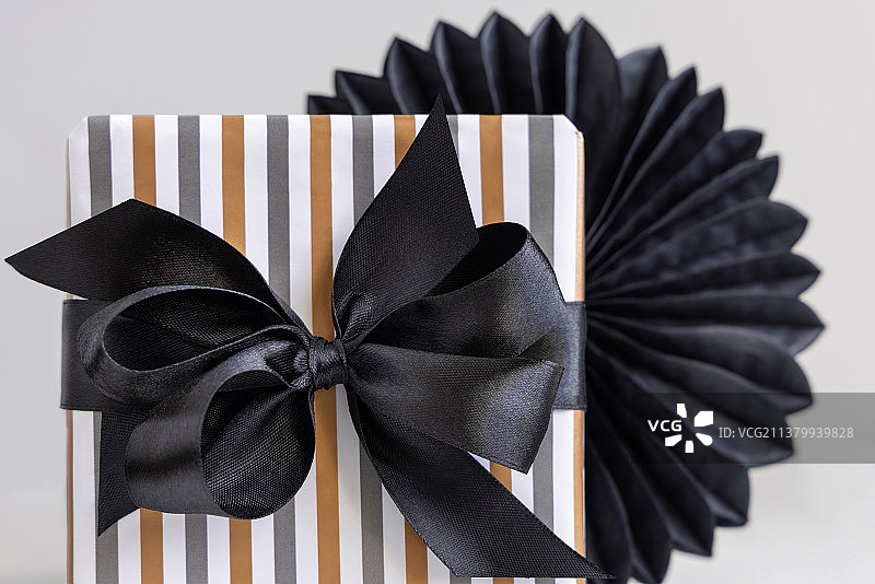 礼品盒包装在条纹纸与黑色丝带蝴蝶结接近图片素材
