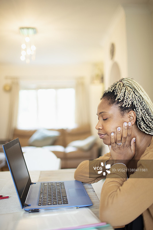 疲惫的女人在家里用笔记本电脑工作图片素材