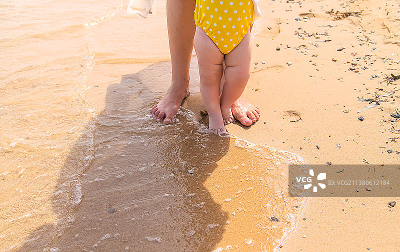 妈妈和宝宝的脚沿着海滩选择性地走着图片素材