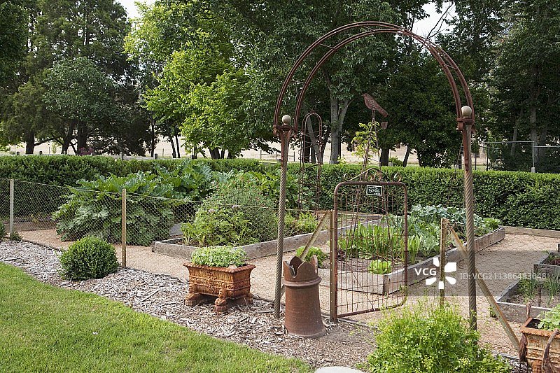 带菜圃的厨房花园-融入了一个历史悠久的花园，但被铁丝网和古老的拱门隔开图片素材