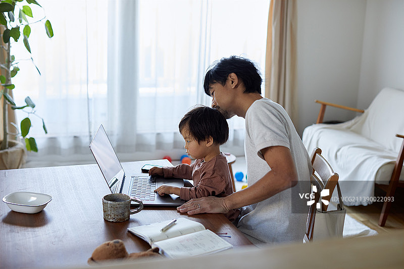 日本男子带着孩子在家工作图片素材