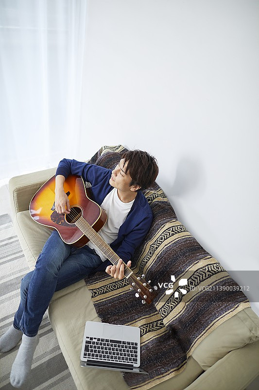 日本男子在家里弹吉他图片素材