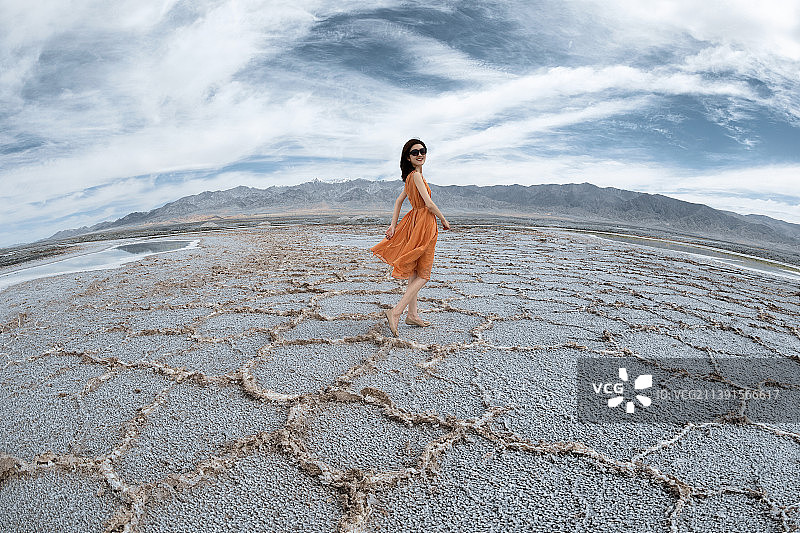 在青海盐湖纹理上迎着天空散步的美女图片素材