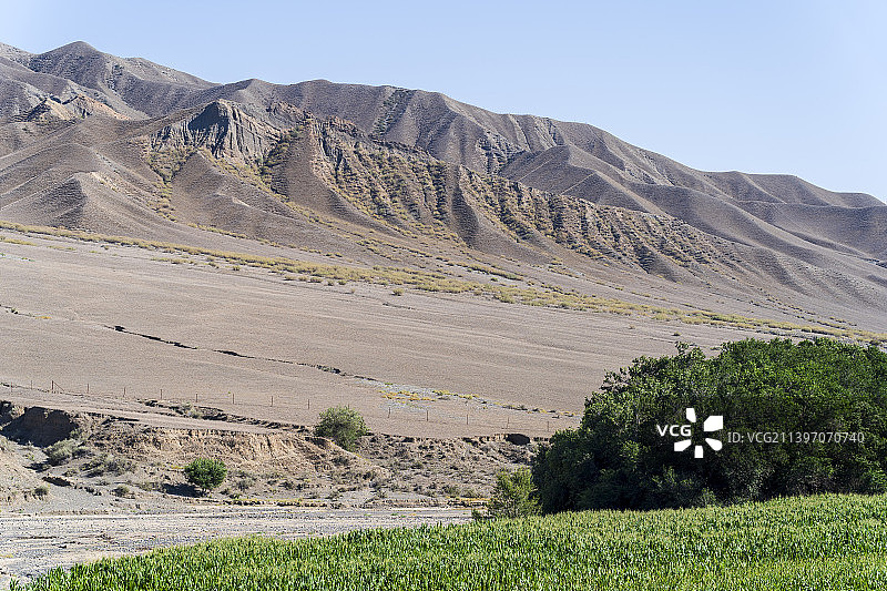 新疆省道S101公路旁雪山脚下的丘陵地貌图片素材