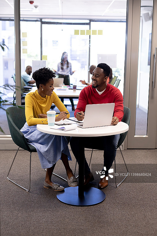 微笑的非洲裔美国女性和男性顾问在办公室用笔记本电脑规划战略图片素材