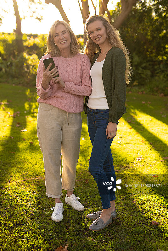 垂直图像的快乐高加索母亲和成年女儿摆相机在秋天的花园图片素材