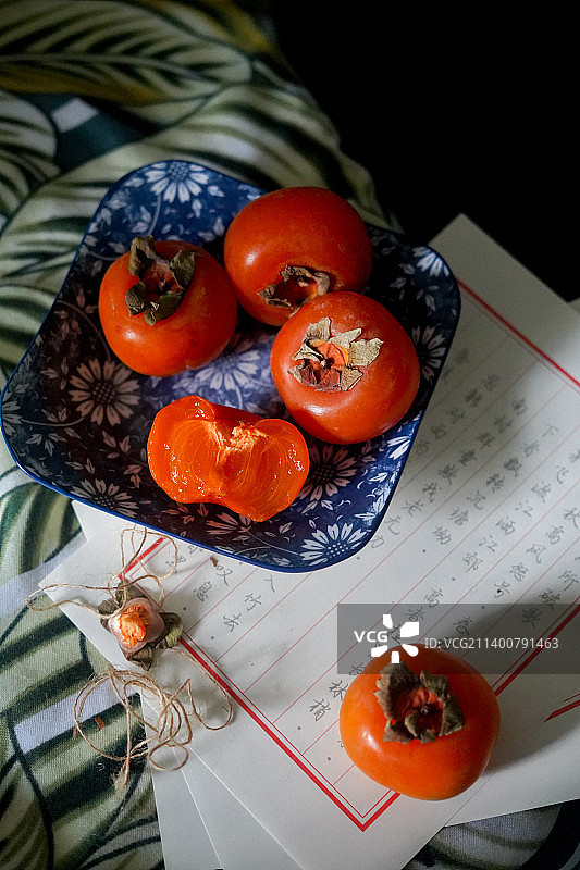 桌上陶瓷盘子里秋天熟透的红色柿子图片素材