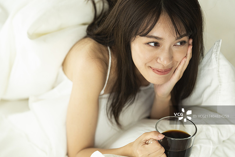 女人躺在床上拿着咖啡杯图片素材