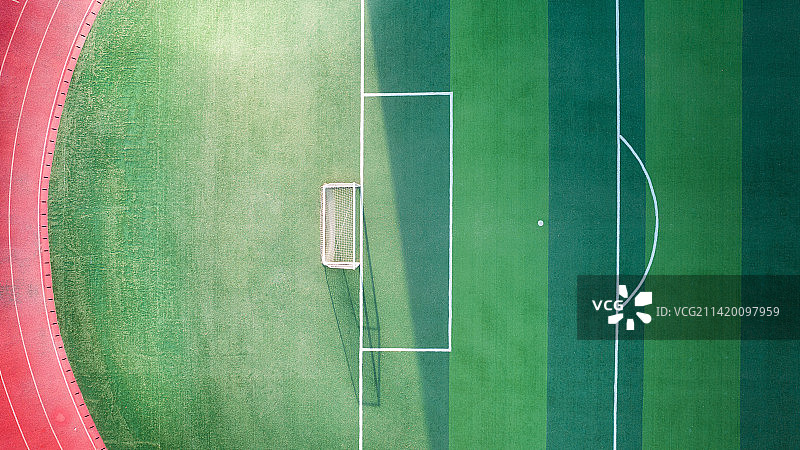 俯视鸟瞰日落时分阳光洒在校园的绿茵足球场上图片素材