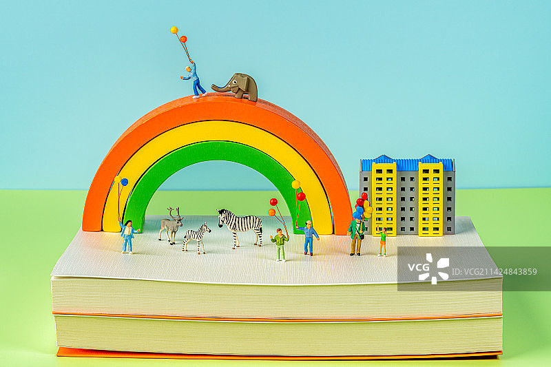 彩虹城市和在书本上玩乐的人和动物创意微缩景观图片素材