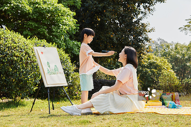 在草坪上绘画的年轻母亲与儿子图片素材