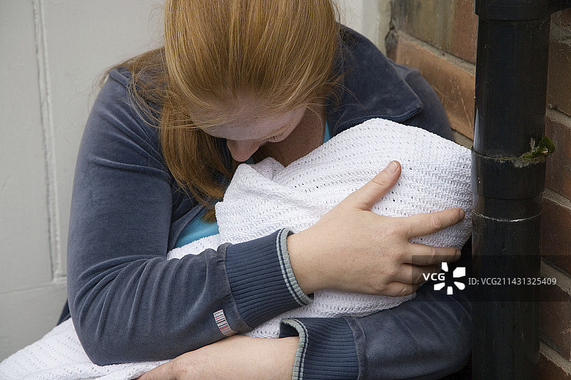 一个女人抱着一个婴儿坐在门阶上图片素材