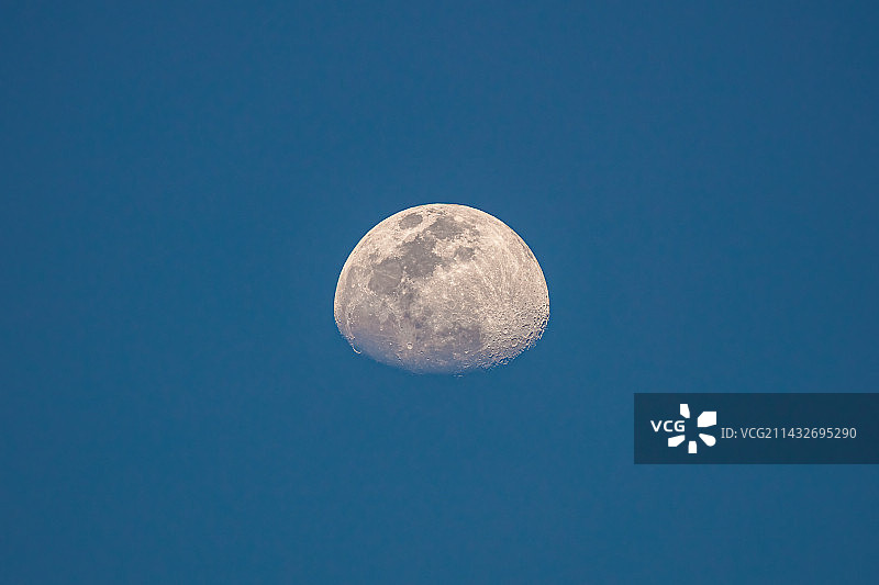 蓝天下农历闰二月十一傍晚的月相特写，月亮只见上半球，呈现凸月形态，月光皎洁，表面有凹凸不平的环形山图片素材