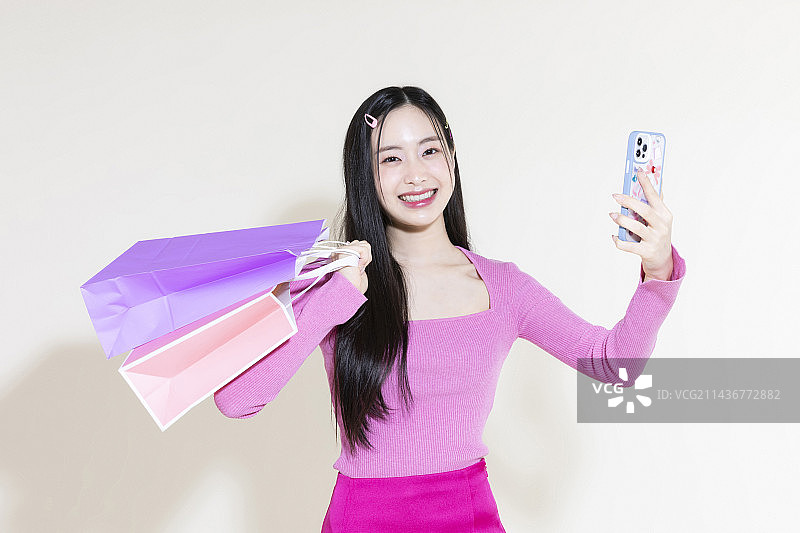 韩国亚洲可爱女子拿着智能手机和购物袋的复古y2k粉色复古概念照片图片素材