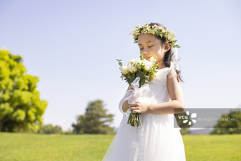 Cute flower girl holding a bunch of flowers图片素材