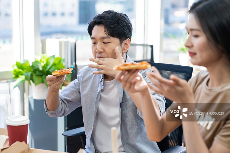 年轻商务人士在办公室加班吃快餐图片素材