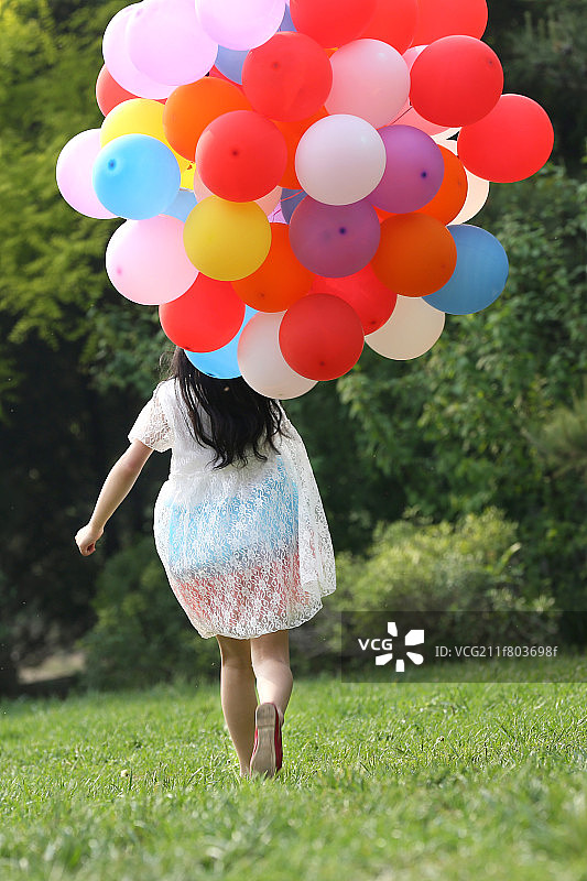 小女孩拿着气球在草地上奔跑图片素材