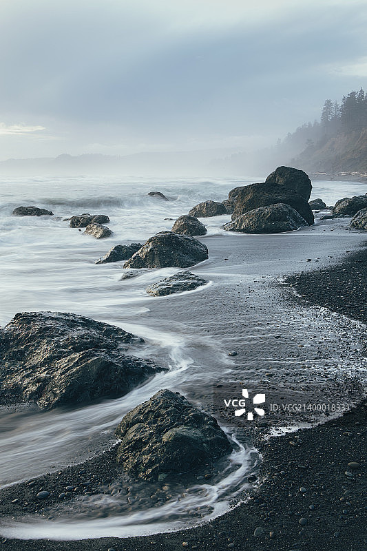海岸线上的岩层在退潮时暴露在海滩上。长时间的曝光。图片素材