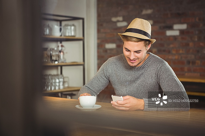 帅气的潮人在咖啡店喝咖啡，用智能手机图片素材