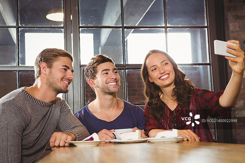 微笑的朋友在咖啡厅喝咖啡和自拍图片素材
