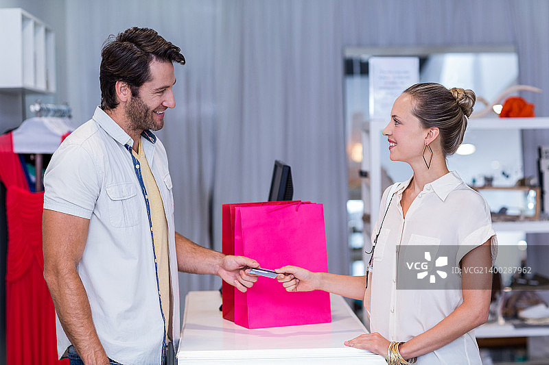 一个微笑的女人在服装店给收银员信用卡图片素材