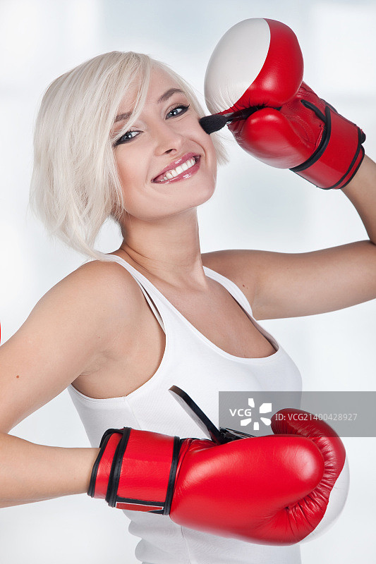 快乐的金发女人戴着拳击手套化妆图片素材