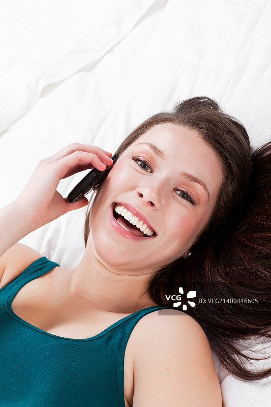 一个漂亮的白人女人躺在床上讲电话图片素材