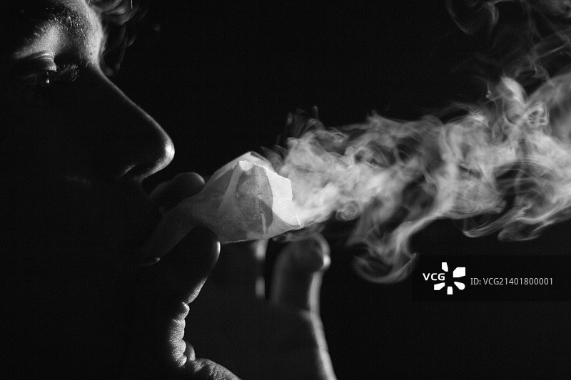 黑色背景下吸烟男子的特写镜头图片素材