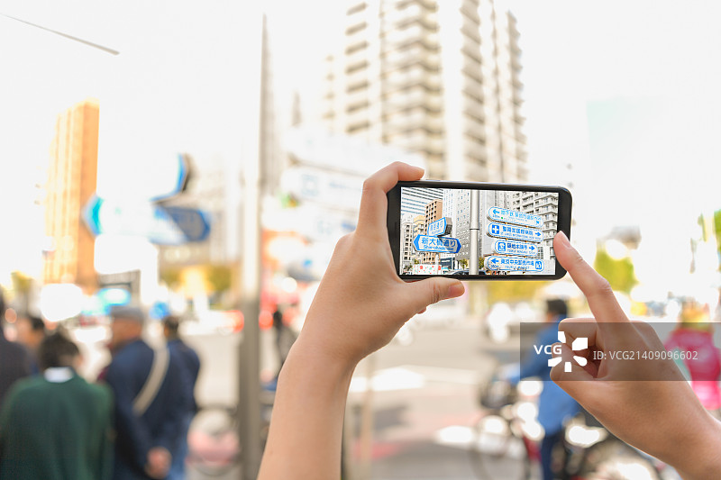 日本女性在智能手机上使用增强现实应用程序，日本东京市区图片素材