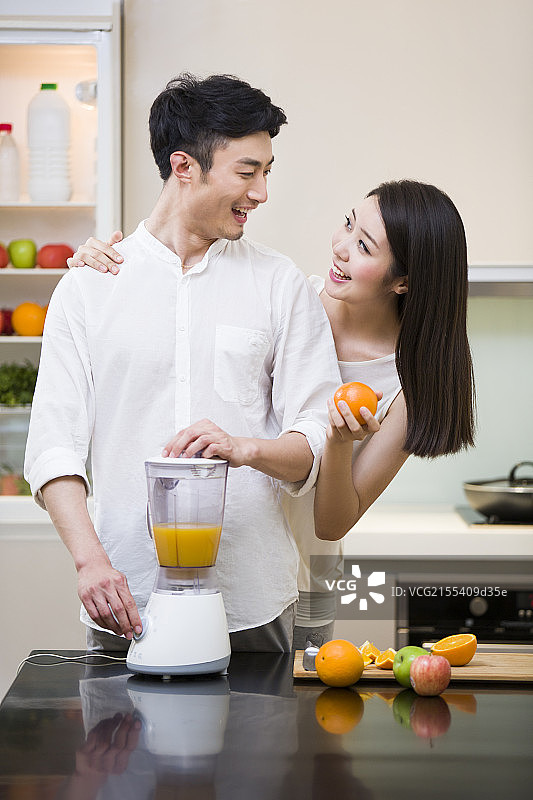 年轻夫妇在厨房使用榨汁机图片素材