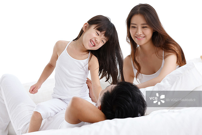幸福的一家三口在卧室的床上玩耍图片素材