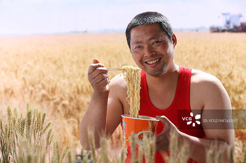 一个农民在麦田里吃方便面图片素材