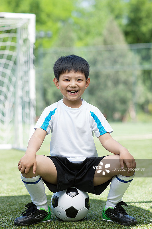 男孩兴奋的坐在足球上图片素材