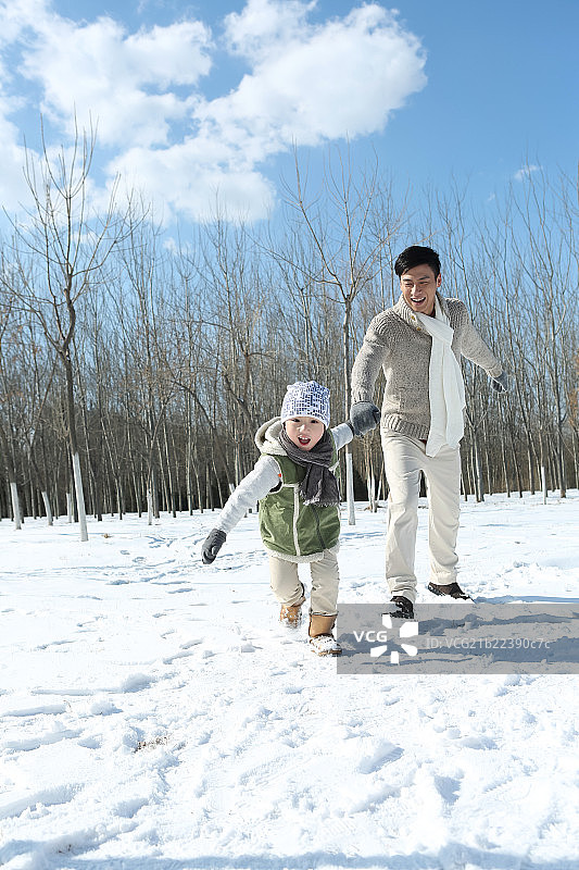 父亲和儿子在雪地上奔跑图片素材