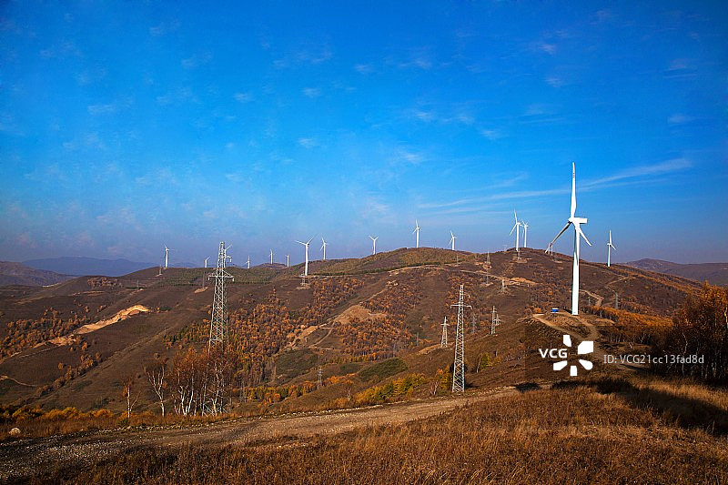 山坡山的风力发电站和输电塔图片素材
