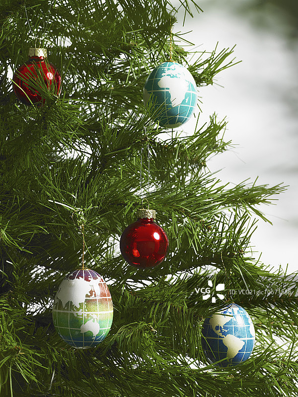 仍然生活。绿叶和装饰物。一根长着绿针的松树树枝。圣诞装饰品。一小群红色和蓝色的圣诞树装饰品。蓝色的背景勾勒出长方形的大陆。图片素材