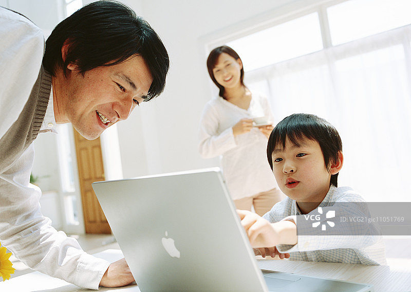 男孩和父亲在桌子上用笔记本电脑图片素材