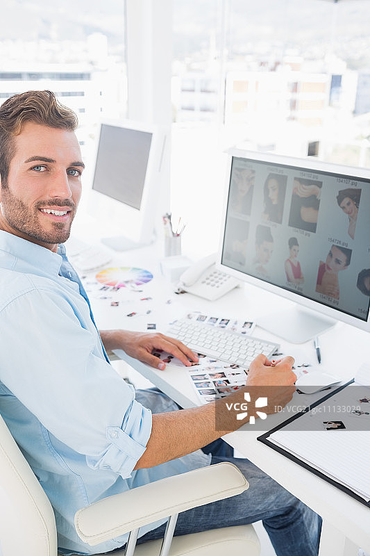 一个男性照片编辑在一个明亮的办公室在电脑上工作的侧视图肖像图片素材