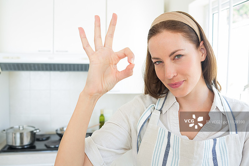 一个微笑的年轻女人在厨房里做手势的特写图片素材