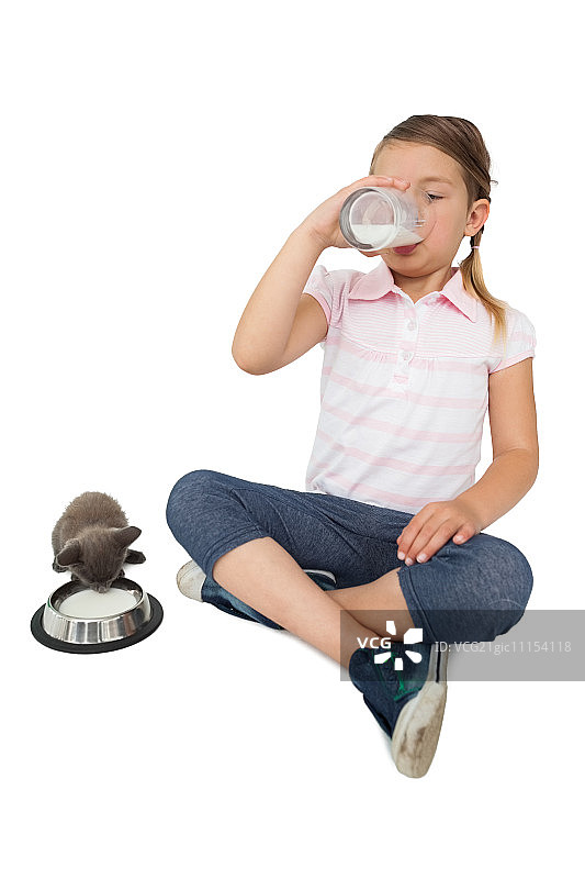 可爱的小女孩和灰色的小猫都喝牛奶在白色的背景图片素材