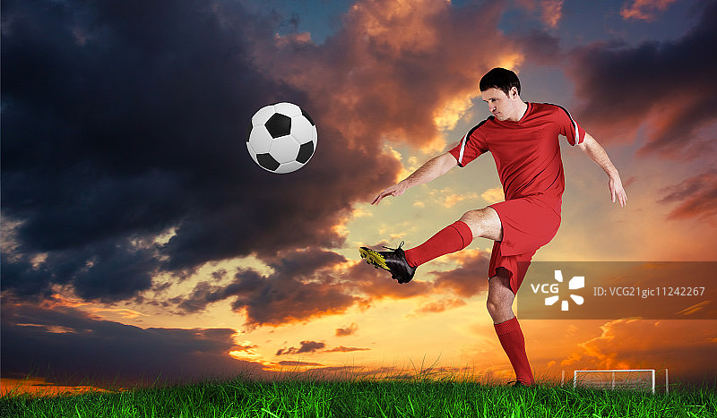 穿着红色衣服的足球运动员在蓝天下踢着绿草图片素材