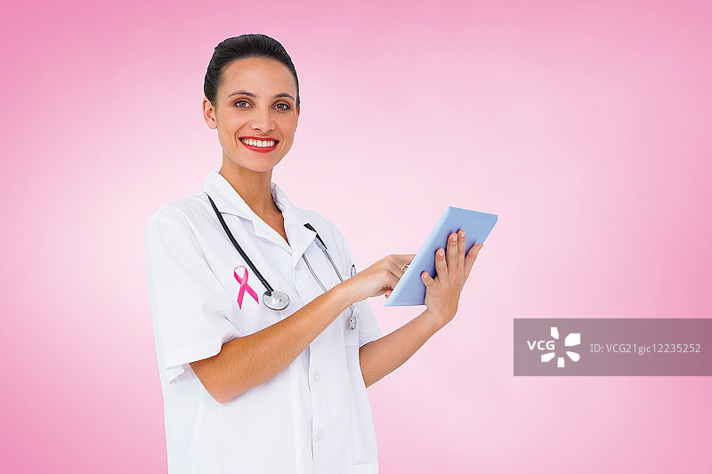 漂亮的护士用平板电脑对抗粉红色的小品图片素材