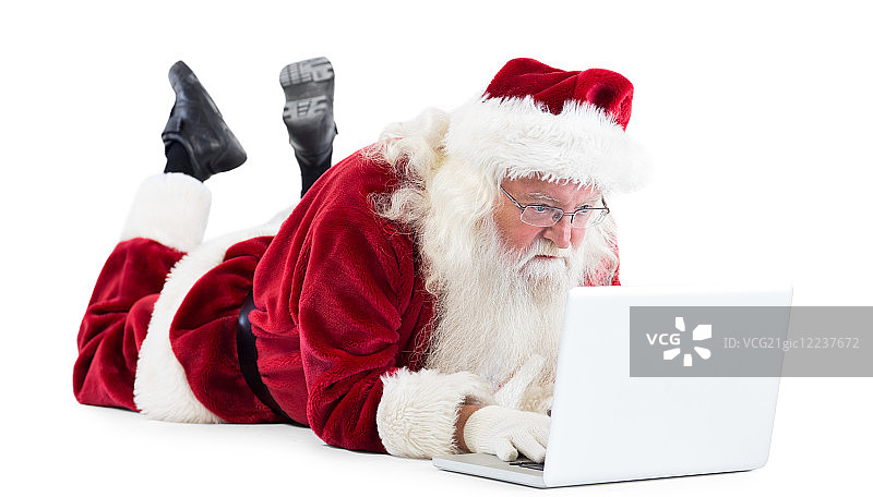 圣诞老人躺在他的笔记本电脑前，白色的背景图片素材