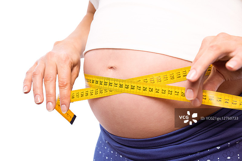 一名孕妇在白色背景下测量自己的肚子图片素材