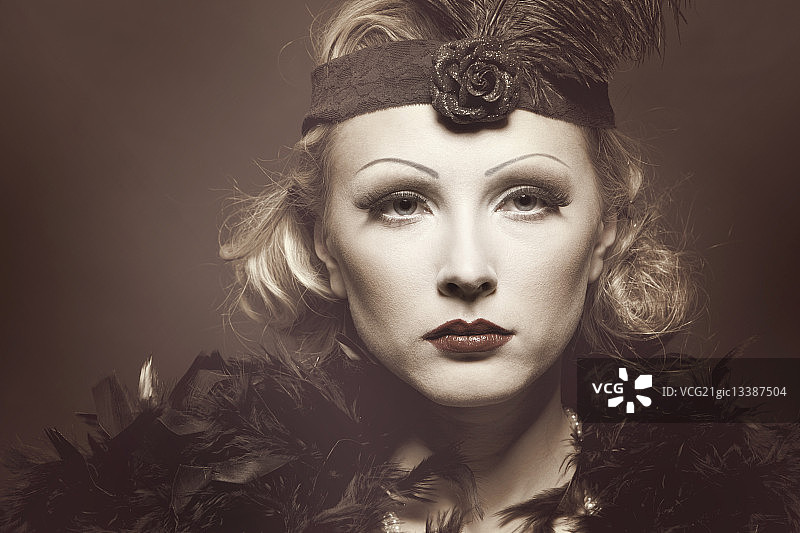 戴着1920年代风格的化妆和头饰的年轻女子。图片素材