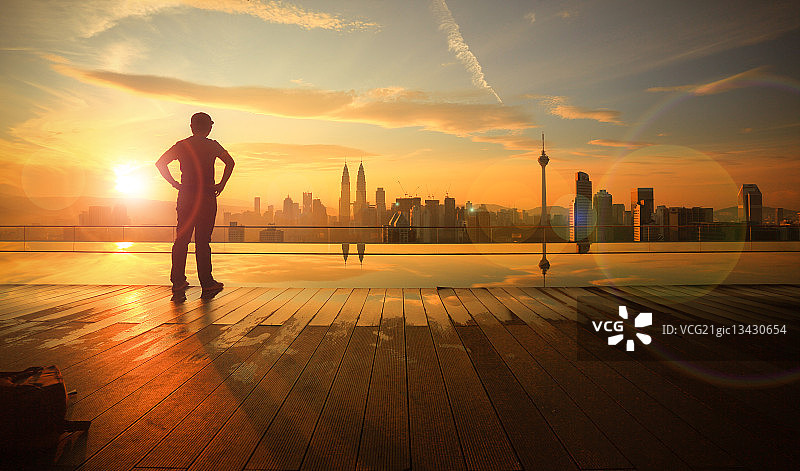 马来西亚吉隆坡城市上空，一个人看着太阳升起的剪影图片素材
