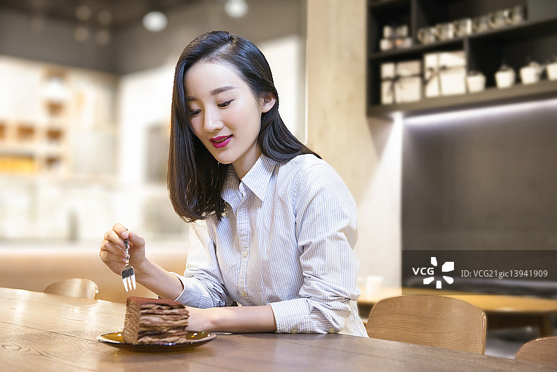 Woman eating cake in bakery图片素材