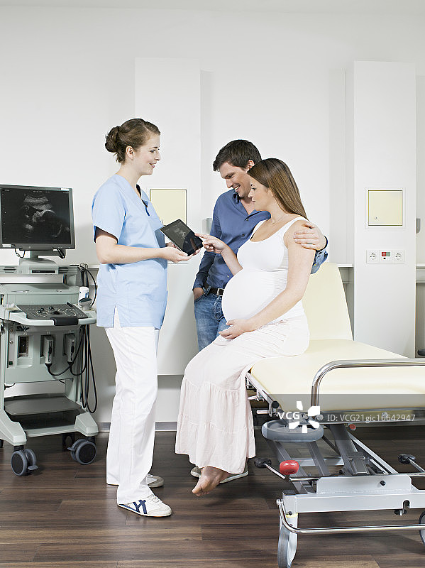 医生用平板电脑显示孕妇和丈夫的超声波扫描图图片素材