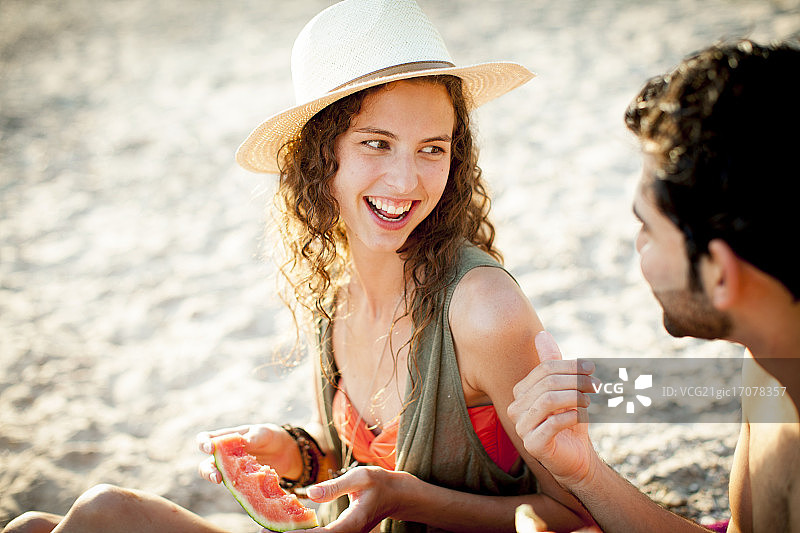 年轻人在海滩上吃西瓜图片素材