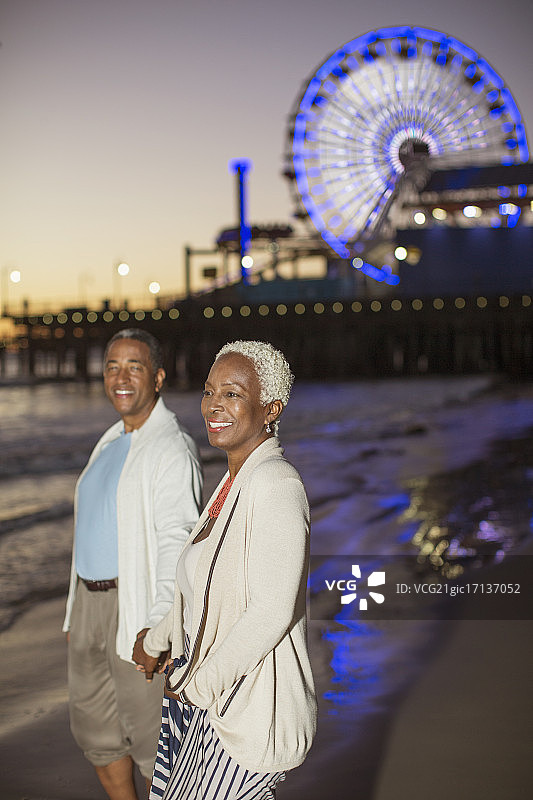 日落时分，一对老年夫妇在海滩上散步图片素材